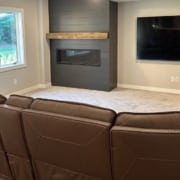 brown leather sectional near window and wall mounted tv - South Metro Custom Remodeling full basement remodel