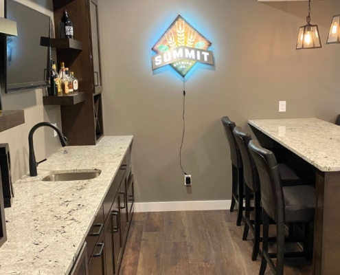 finished basement with a full kitchen and lit bar sign - South Metro Custom Remodeling basement contractor
