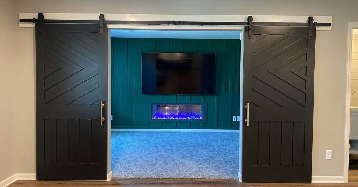 finished basement with a wall mounted tv and barn style doors - South Metro Custom Remodeling basement remodeling ideas