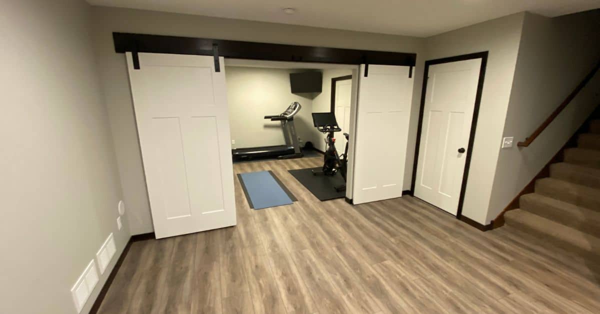 finished basement with white barndoors leading to home gym - South Metro Custom Remodeling basement contractor