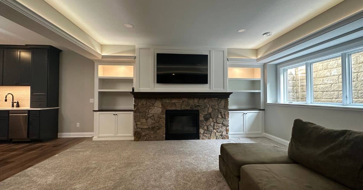 finished basement with rock fireplace and white cabinetry - South Metro Custom Remodeling custom basement remodeling