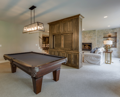A billiard table in a cozy room featuring a couch and television, enhancing the space to increase home value with basement remodel.